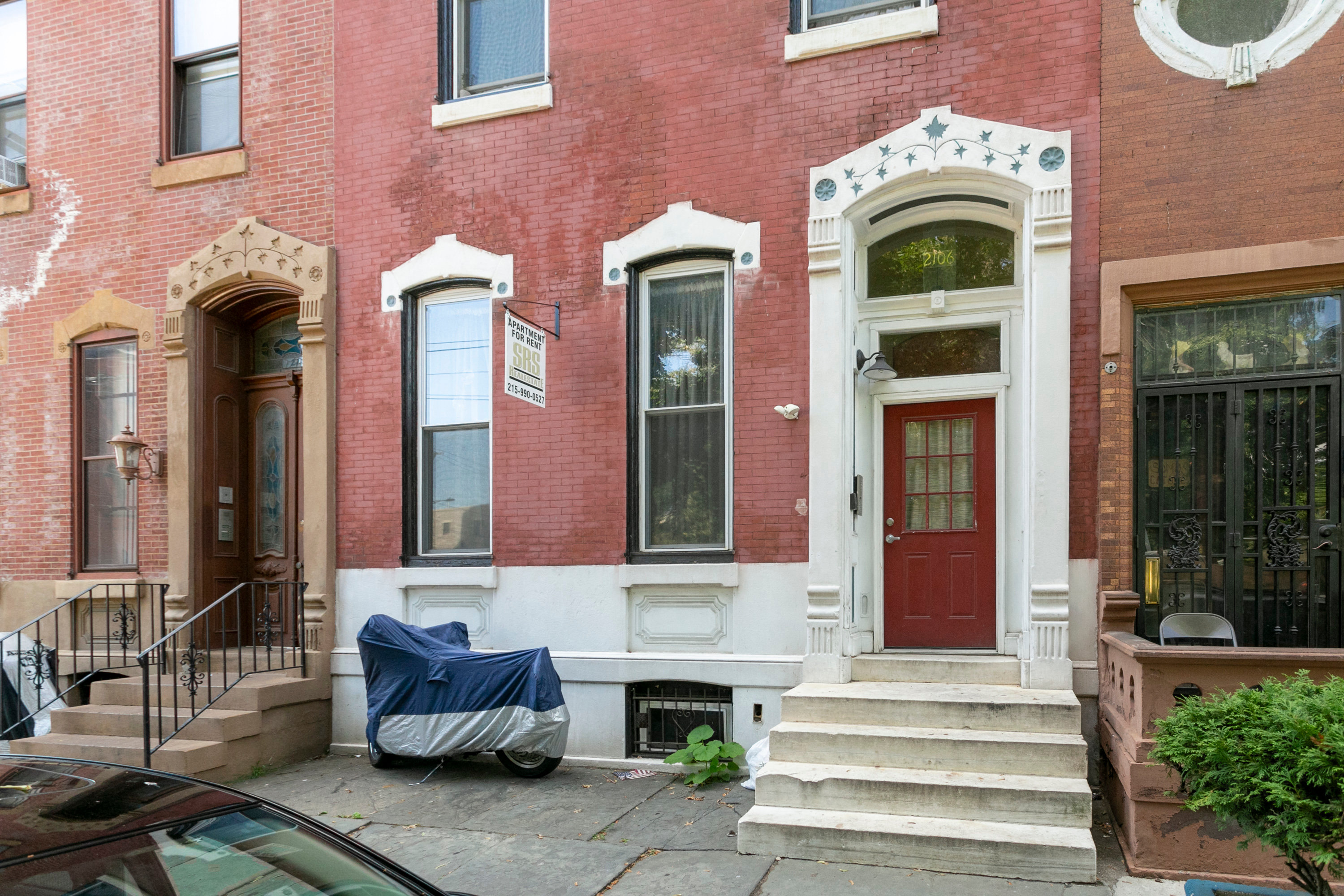 the front of a brick house with a red door